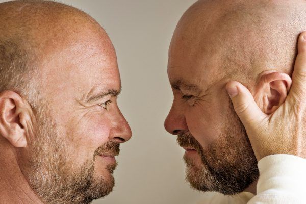 uomini adulti calvi che si guardano emotivamente faccia a faccia