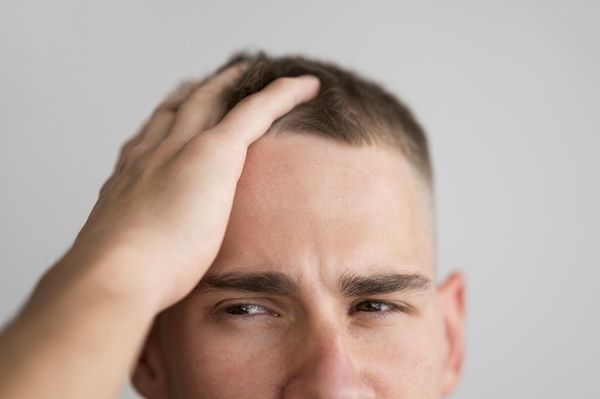 uomo che si avvicina toccandosi la testa