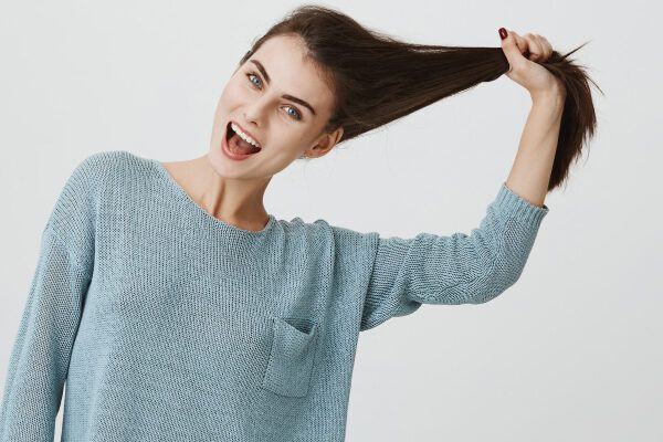 donna caucasica con un viso felice che si tira i capelli verso l'alto