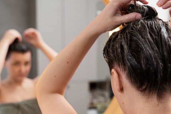 Donna che si prende cura dei suoi capelli - Donna in bagno che si applica dei prodotti sui capelli. Cosa sono gli scrub?