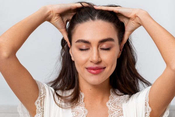 Donna che si massaggia il cuoio capelluto e sembra soddisfatta dei suoi capelli.