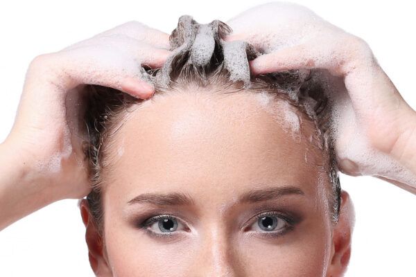 Donna con schiuma tra i capelli - Donna che si lava i capelli. Consigliato dopo l'esfoliazione.
