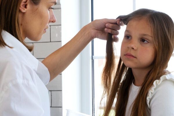 Madre che esamina il cuoio capelluto della figlia dall'aspetto biondo.
