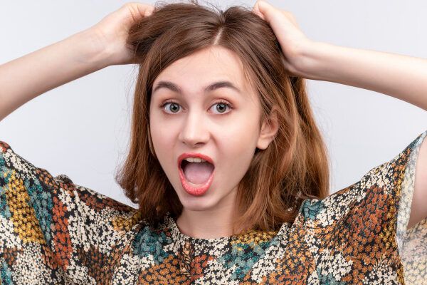 Giovane che sembra sorpreso prendendo i suoi lunghi capelli castani.