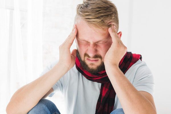 Uomo affaticato e stressato che si tocca le orecchie mentre è seduto - Calvicie influisce livello psicologico