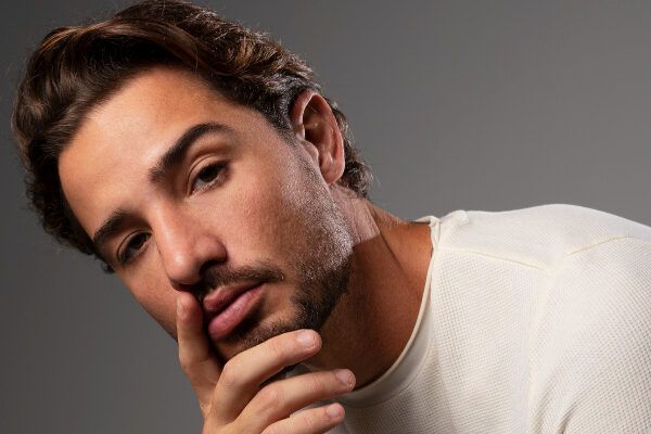 Giovane con barba e capelli castani che posa con un'espressione di modello alla macchina fotografica - Capelli sani dall'interno.