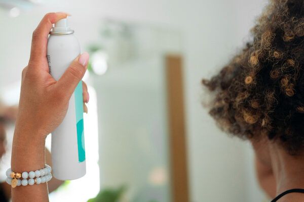 Donna dalla pelle scura che usa uno shampoo spray di buona qualità.