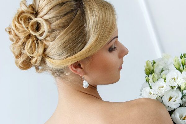 Bella donna bionda vestita da sposa con un'acconciatura armata e un mazzo di fiori tra le mani -Acconciature da evitare.