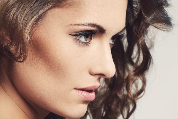 Donna con occhi castani e capelli ricci truccata in posa con un profilo di modella per le sue fotografie.