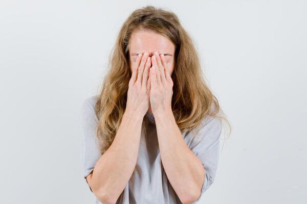 Donna con capelli biondi danneggiati che le coprono il viso con un'espressione preoccupata - Effetto shedding.