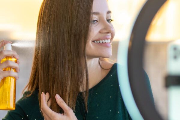 Giovane con i capelli corti che registra una scena mentre applica con cura un prodotto sui capelli.