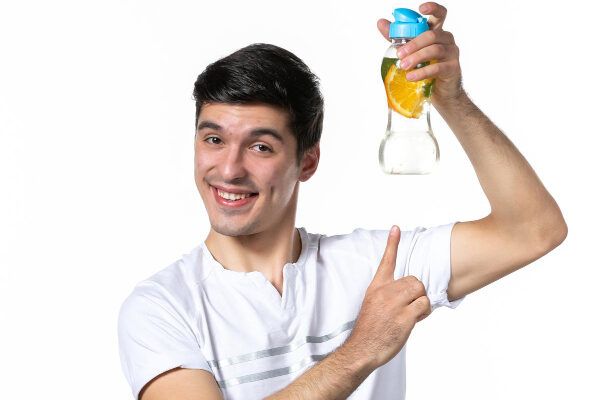 Giovane in flanella bianca sorridente con una bottiglia in mano e l'altra che ne indica il contenuto - Piscine influisce sui capelli.