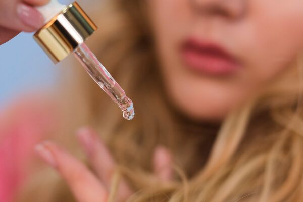 Donna bionda che applica gocce sulle punte dei capelli come cura speciale.