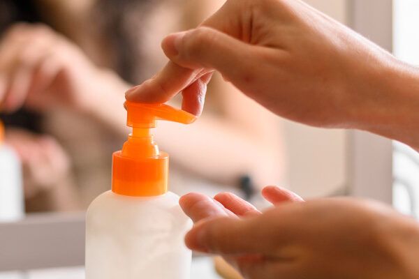 Primo piano di una mano che estrae la crema da un dispenser