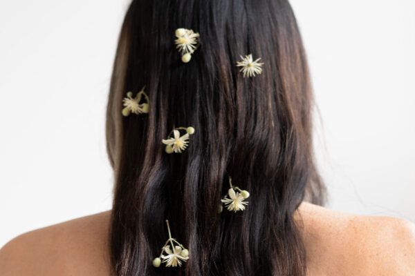 Donna con lunghi capelli castani da dietro con fiori tra i capelli - Il pH dei capelli.