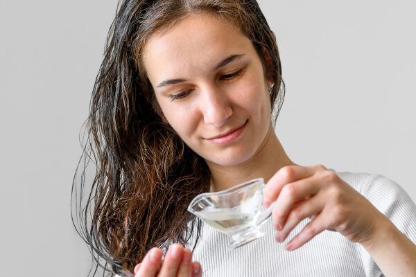 Donna sorridente che applica il siero sulle punte dei capelli bagnati.