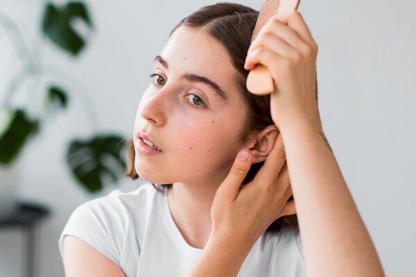 Ragazza che si pettina i capelli con una spazzola cellulare - Il pH dei capelli.