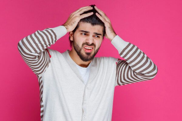 Giovane con maglione a strisce che guarda diagonalmente con espressione confusa.