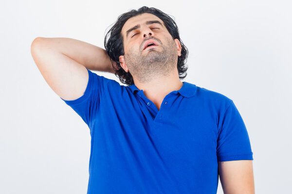 Uomo adulto di corporatura robusta con capelli lunghi e barba tirata indietro con un'espressione particolare - Sindrome dei capelli impettinabili.