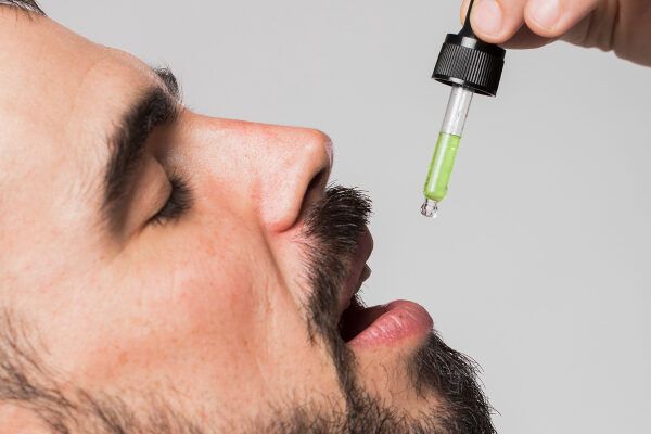 Uomo adulto con barba che prende gocce speciali.