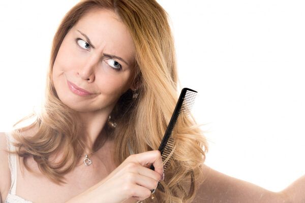 Donna bionda che si pettina i capelli con una spazzola a setole.