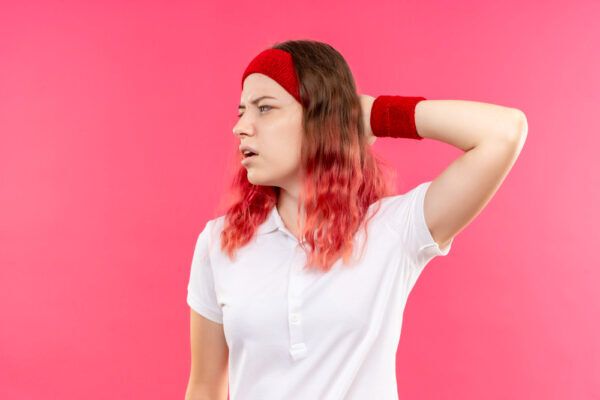 Ragazza con capelli tinti di rosa e ondulati che utilizza bandana e braccialetti per esercizi.