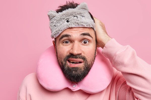 Uomo arruffato con un maglione addormentato e un viso sulla fronte con un'espressione disorientata - Insonnia influisce sui nostri capelli.