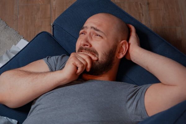 Uomo calvo in una situazione emotiva difficile e disteso preoccupato sui suoi mobili.