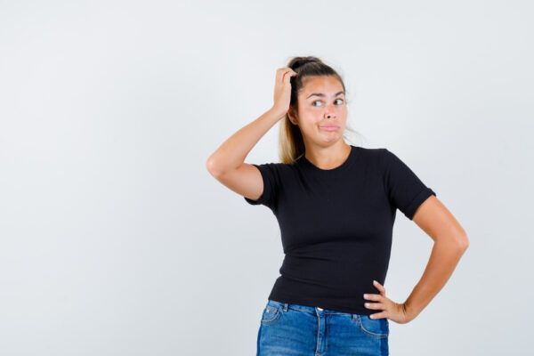Ragazza con i capelli legati in una coda alta che si gratta la testa mentre guarda di lato con un'espressione dubbiosa.
