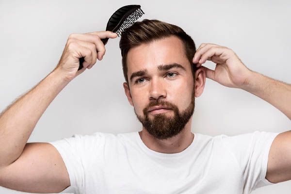 uomo che si pettina i capelli pensieroso