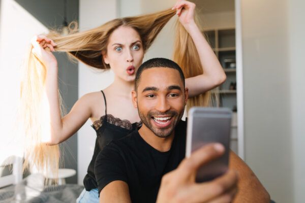 Ragazzi in una stanza si divertono mentre scattano foto con i cellulari, mettendo in risalto i loro capelli.