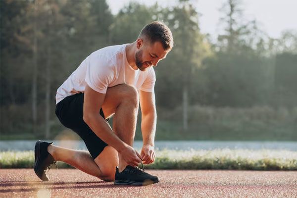 Un jogger si allaccia le scarpe su una pista