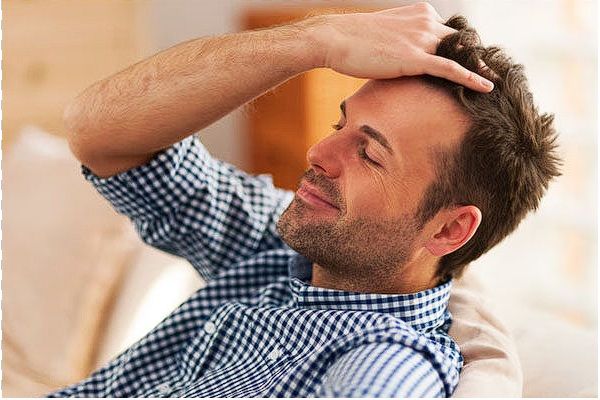 Uomo maturo seduto rilassato che si sistema i capelli con la mano