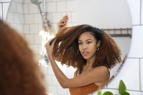 Donna che si pettina i capelli ricci davanti allo specchio