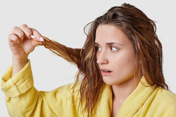 Una donna con i capelli unti guarda i suoi capelli ricci