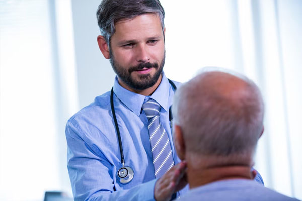 un giovane medico esamina un paziente anziano calvo